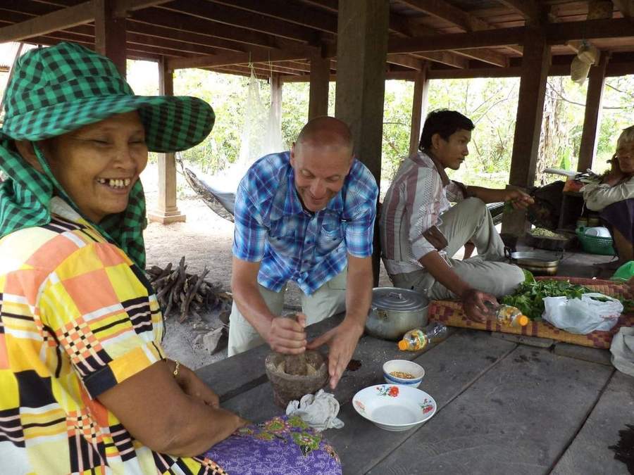Volunteer with local family near wooden cart and bamboo