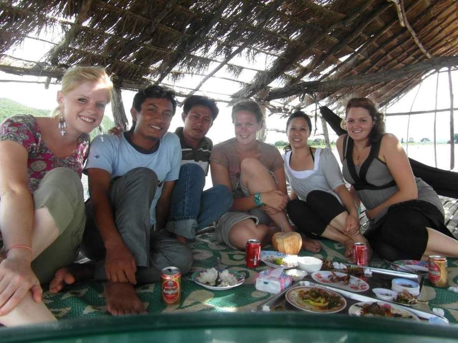 Volunteers and locals sharing meal under thatched shelter