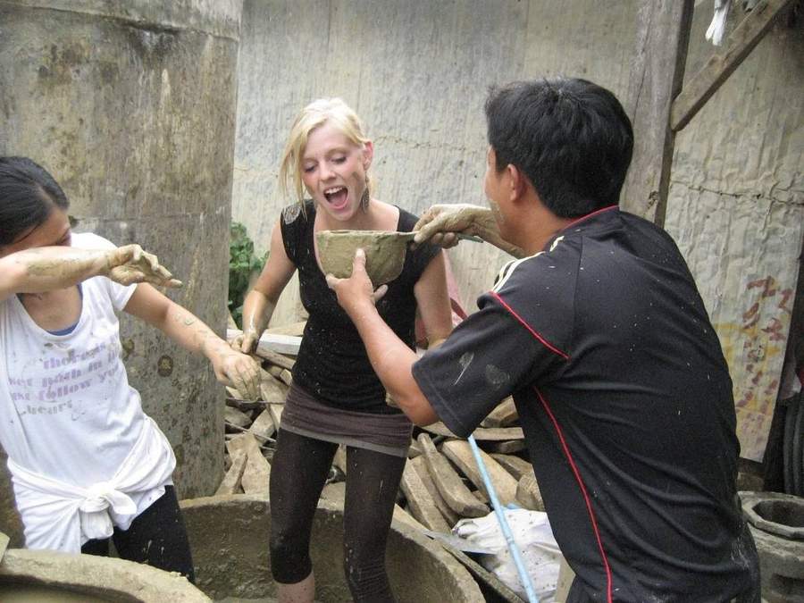 Volunteer covered in clay while making pottery with locals