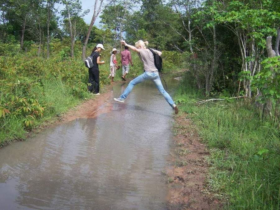 Volunteer jumping across flooded section of forest trail
