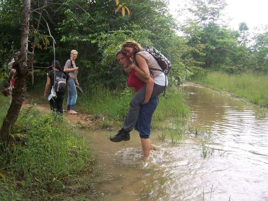 Volunteer carrying person through flooded road with backpacks