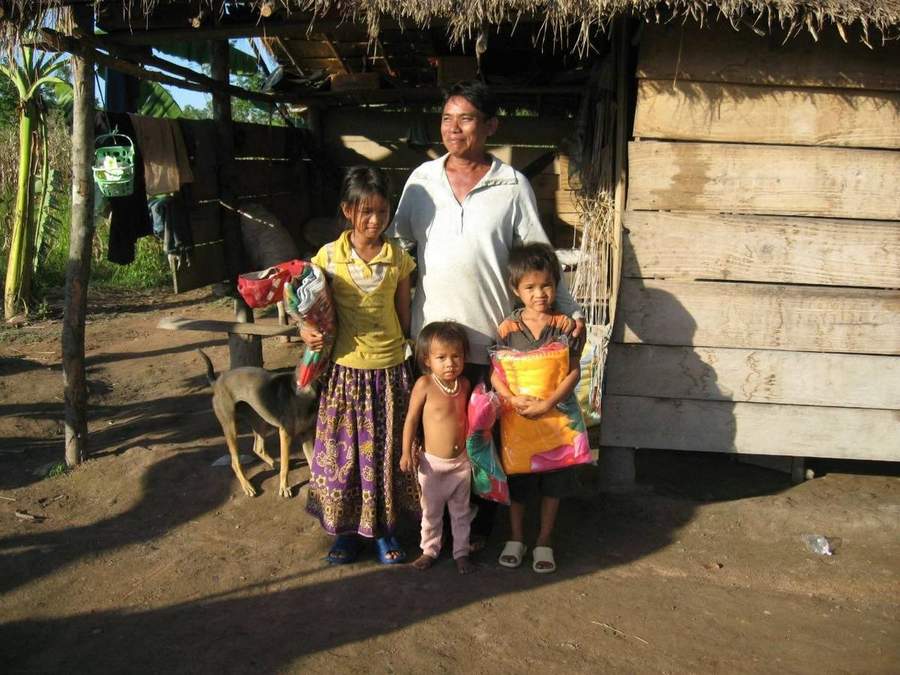 Mother with children standing near their wooden house