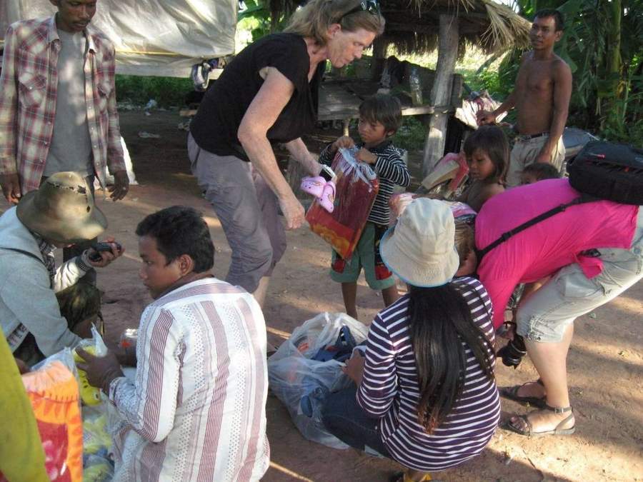 Volunteer handing out clothing to villagers with photographer