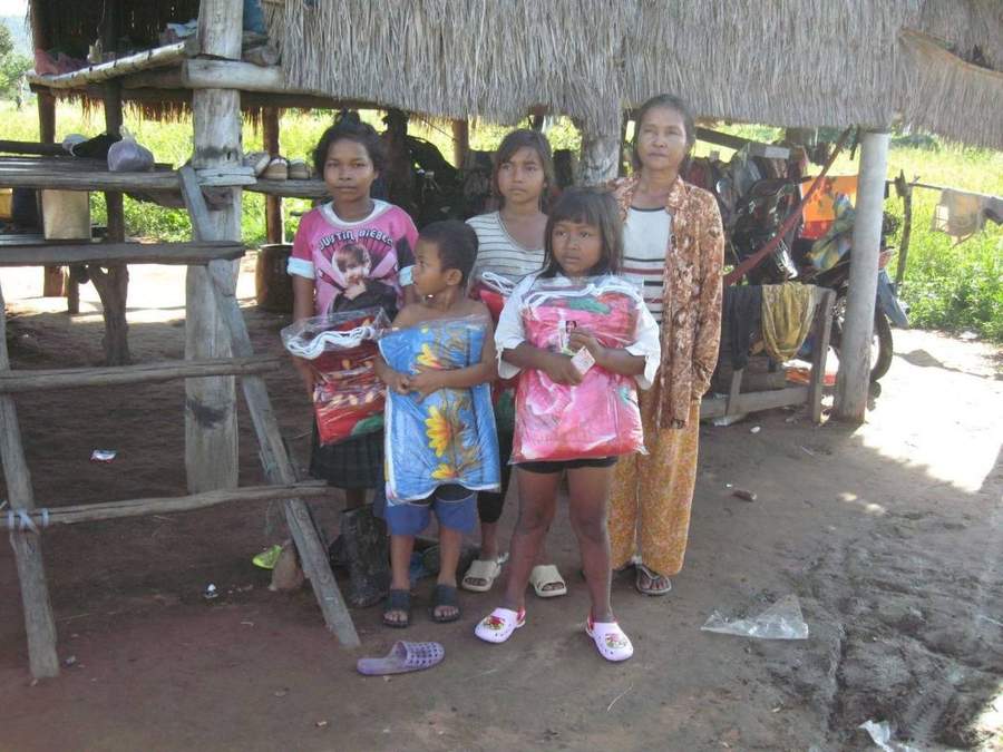 Group of children and adults with supplies near bamboo structure