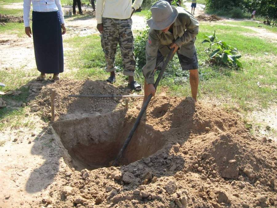 Community members digging large pit for construction project