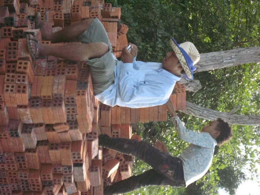 Two men working with stack of red bricks outdoors