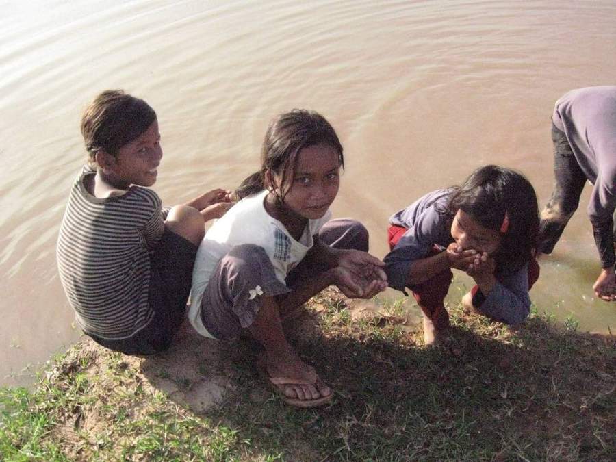 Children playing in muddy brown river water