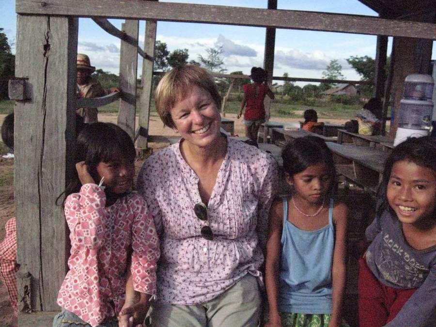 Volunteer smiling with children at open-air school