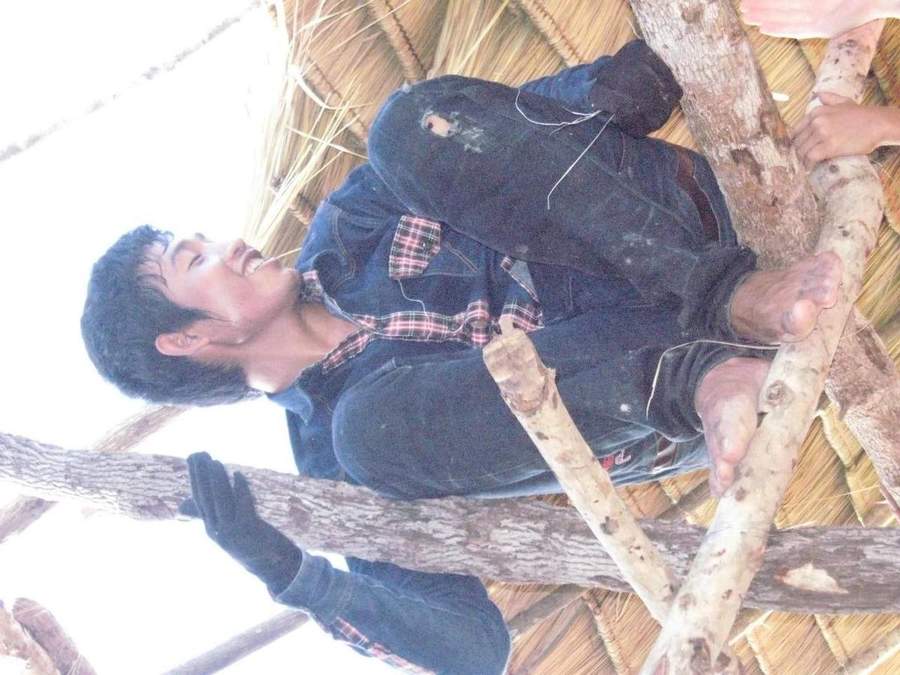 Man sitting on wooden roof beams during construction