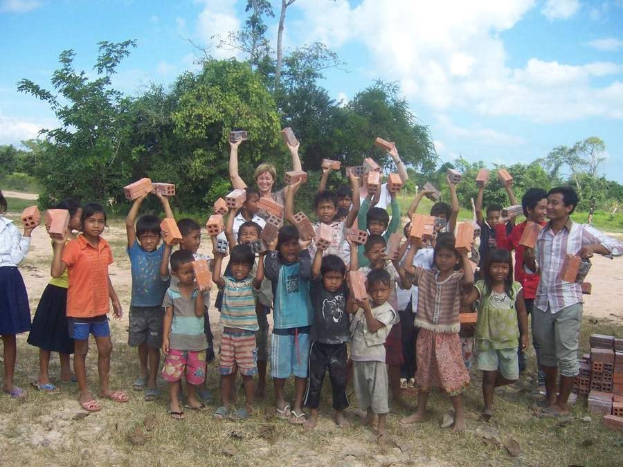Large group of children holding bricks with volunteer