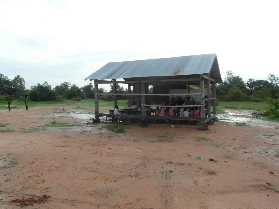 Raised school building with metal roof on muddy ground