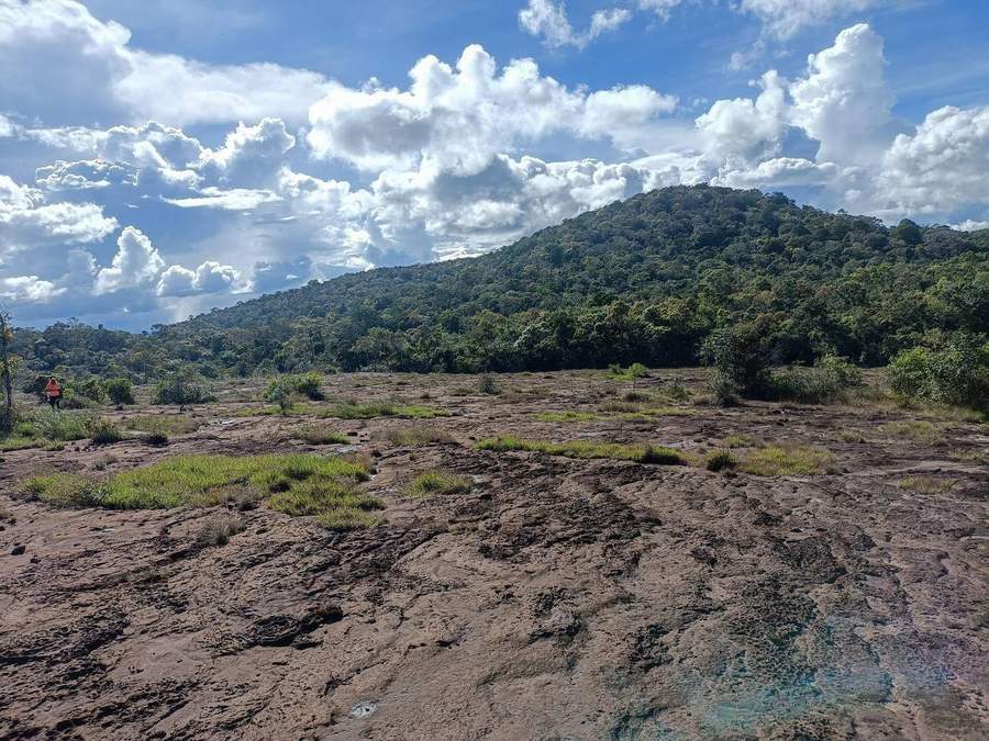 Rocky plateau landscape with forested mountain in distance