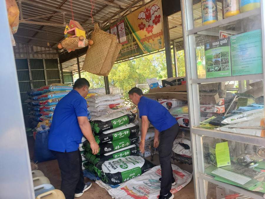 Workers handling fertilizer bags in agricultural supply shop
