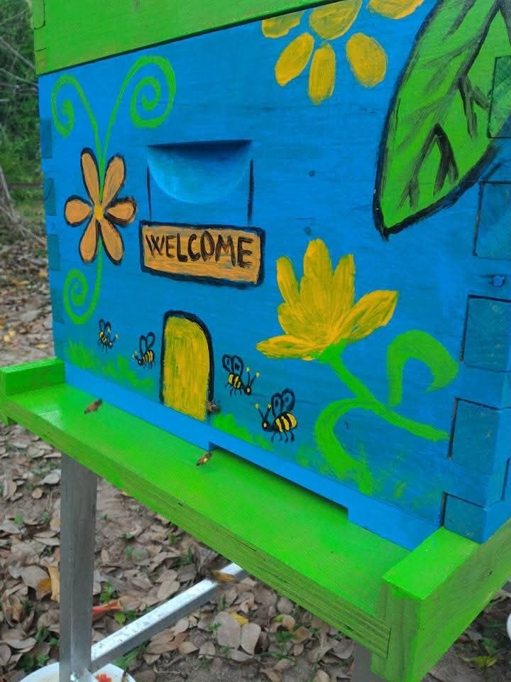 Colorful painted beehive with welcome sign and bee decorations