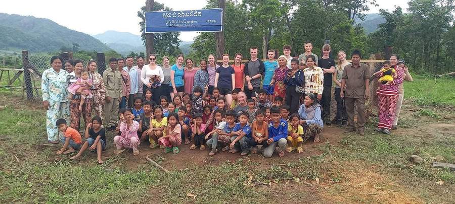 Large group photo at La Petite School Garden sign