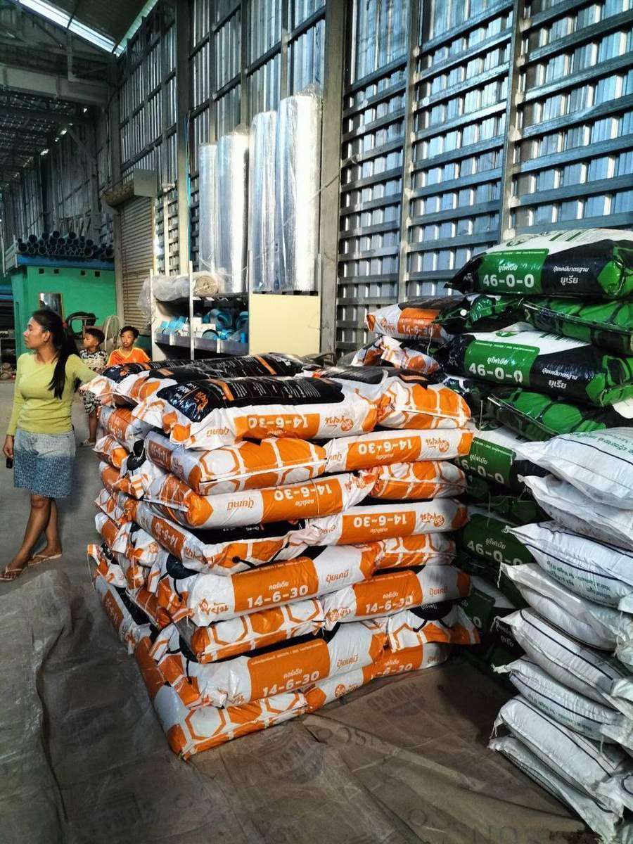 Woman and child near fertilizer bags in warehouse