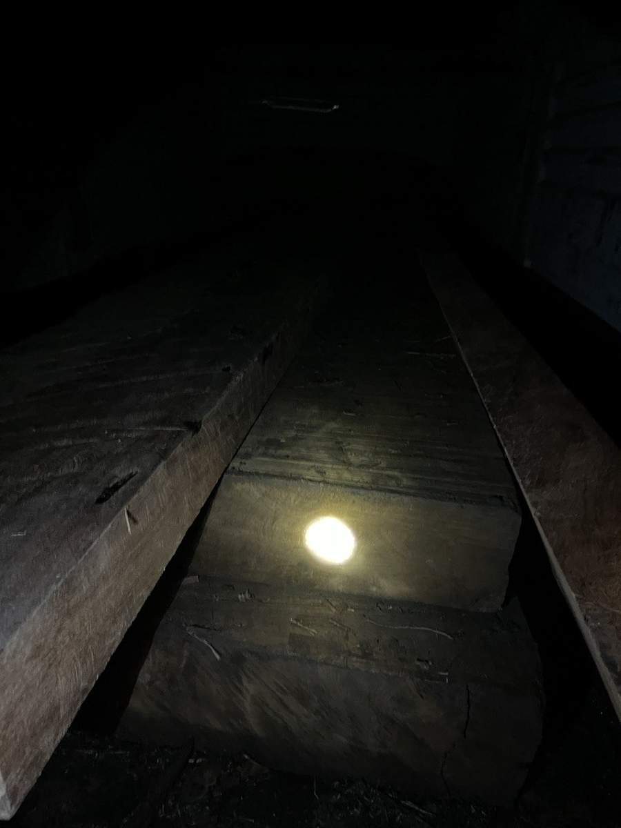 Flashlight illuminating seized timber planks in dark storage