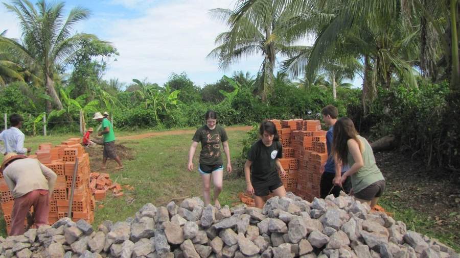 Volunteers working with rocks and bricks at construction site