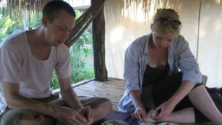 Man and woman sitting on bamboo floor preparing food