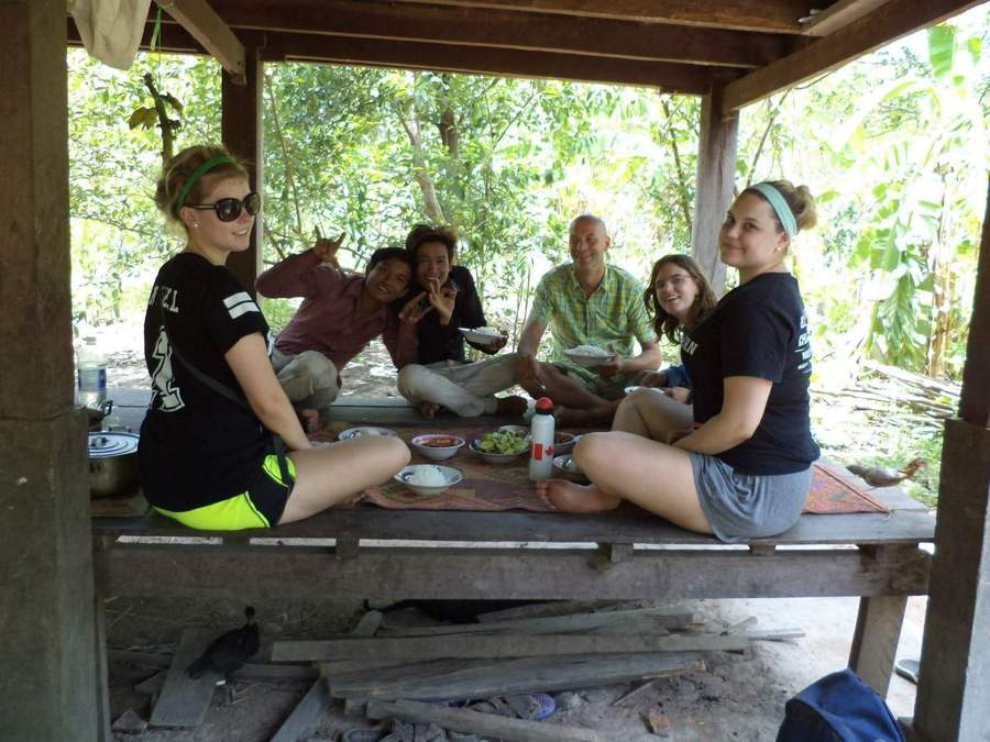 Group sitting on wooden platform sharing meal together