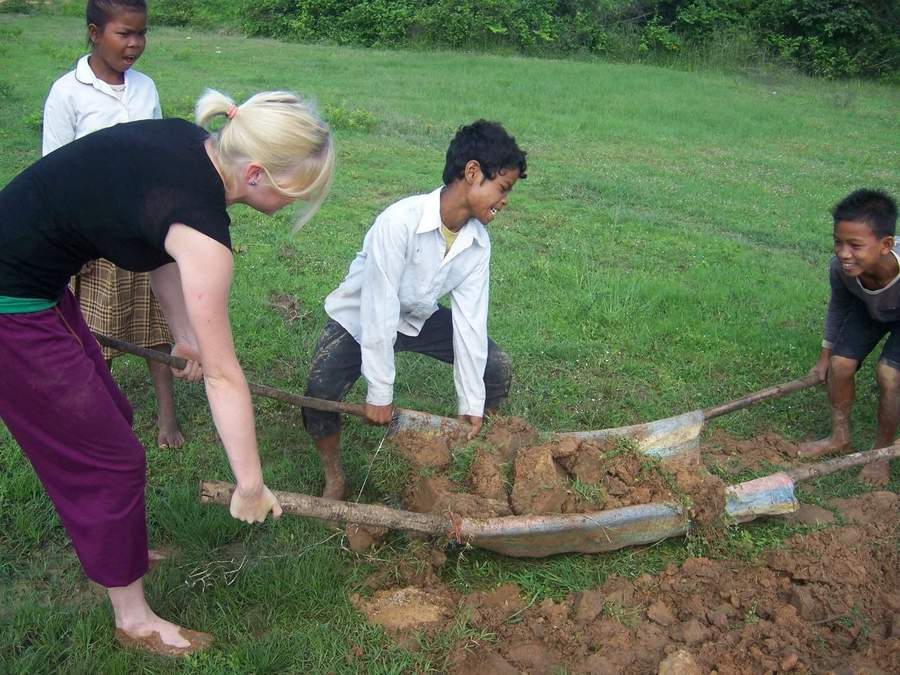 Volunteer and children digging with hoes in grassy field