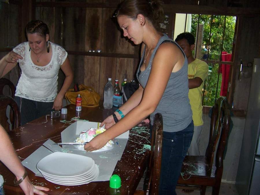 Women cutting cake at table with paper plates at celebration