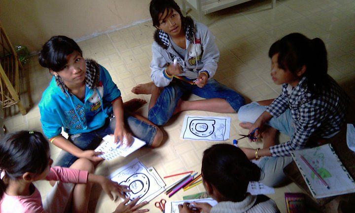 Children sitting on floor doing art activity with coloring pages