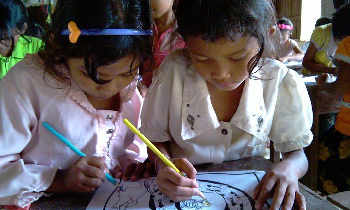 Two girls coloring at desk with crayons and markers
