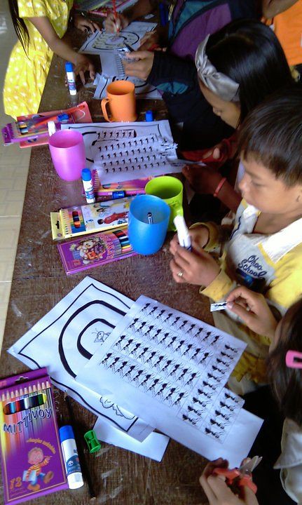 Children doing art activity at table with craft supplies and cups