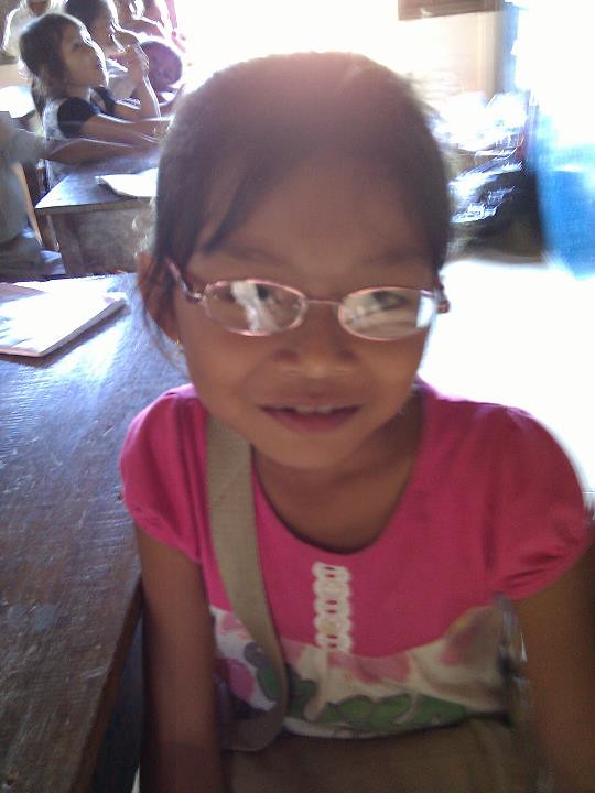 Young girl with glasses smiling in classroom