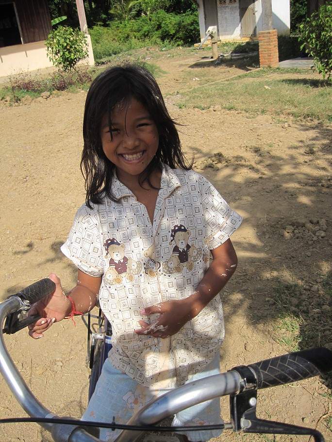 Young girl smiling while holding bicycle handlebars