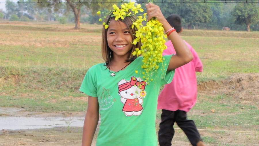 Girl wearing yellow flower crown holding yellow flowers in field