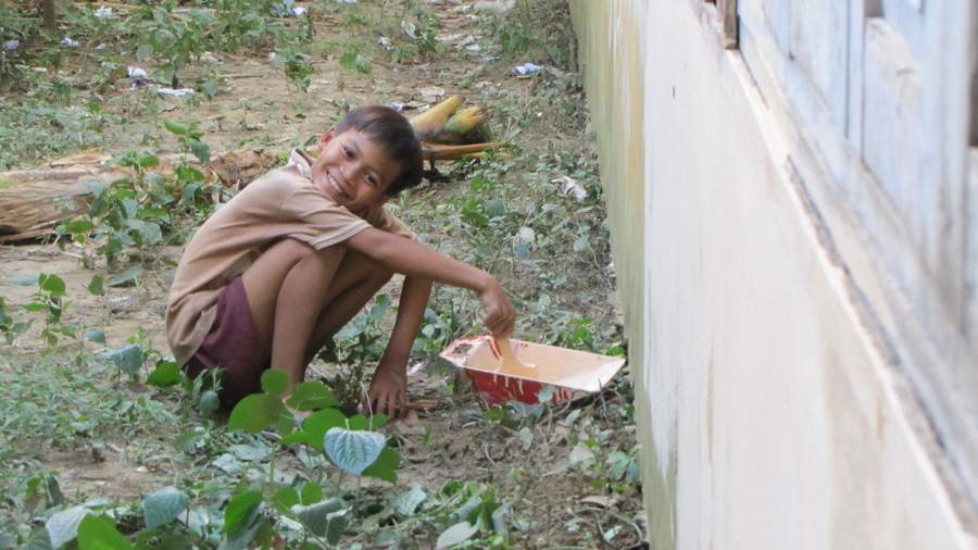 Boy crouching beside building wall outdoors