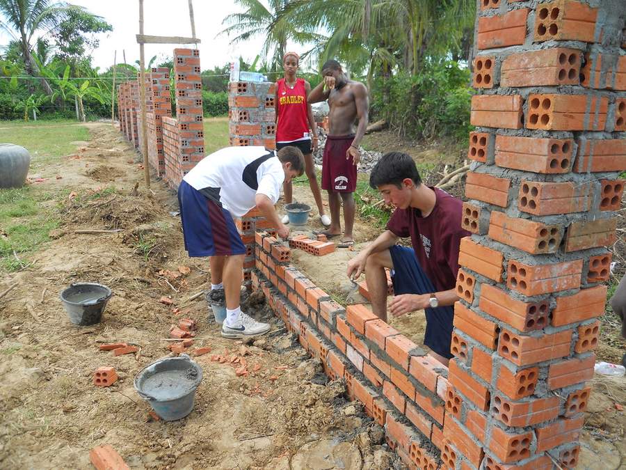 Volunteers and locals building brick wall at construction site