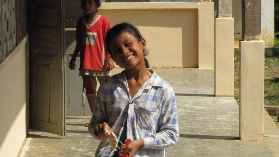 Girl holding paintbrush smiling in doorway of building