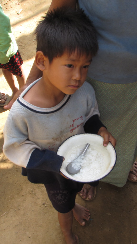 Young boy holding bowl of rice with spoon