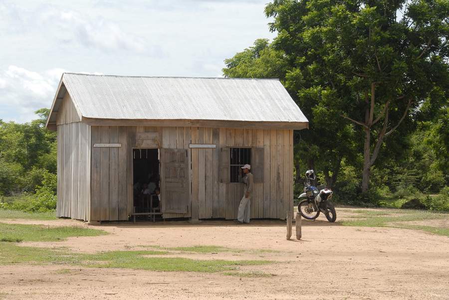 Wooden school building with corrugated metal roof and motorcycle