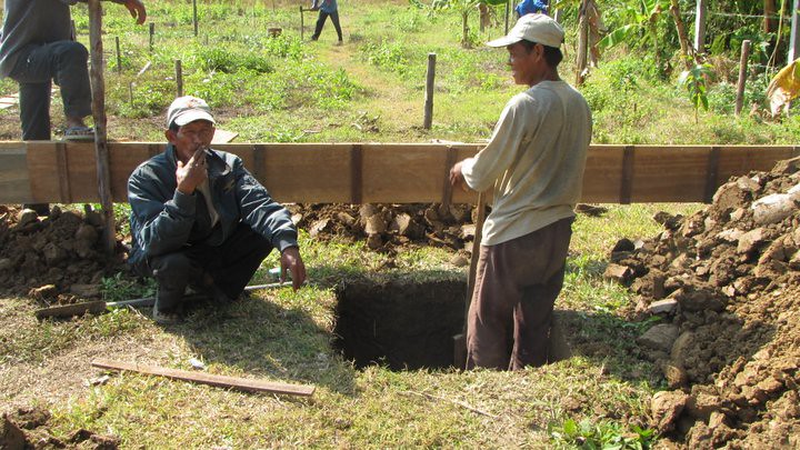 Workers digging foundation trench with wooden form