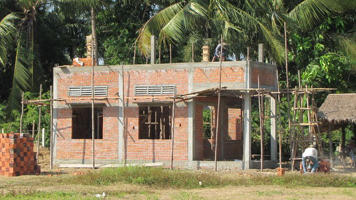 Brick building under construction with workers on roof