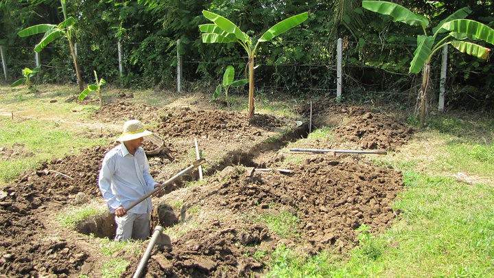 Worker standing in foundation trench with dirt piles
