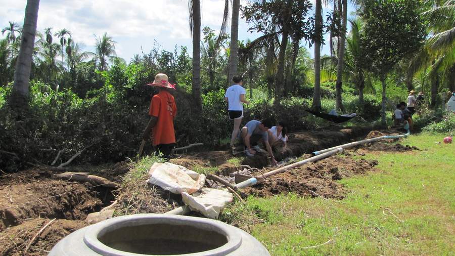 People working in trench laying pipes with concrete water jar