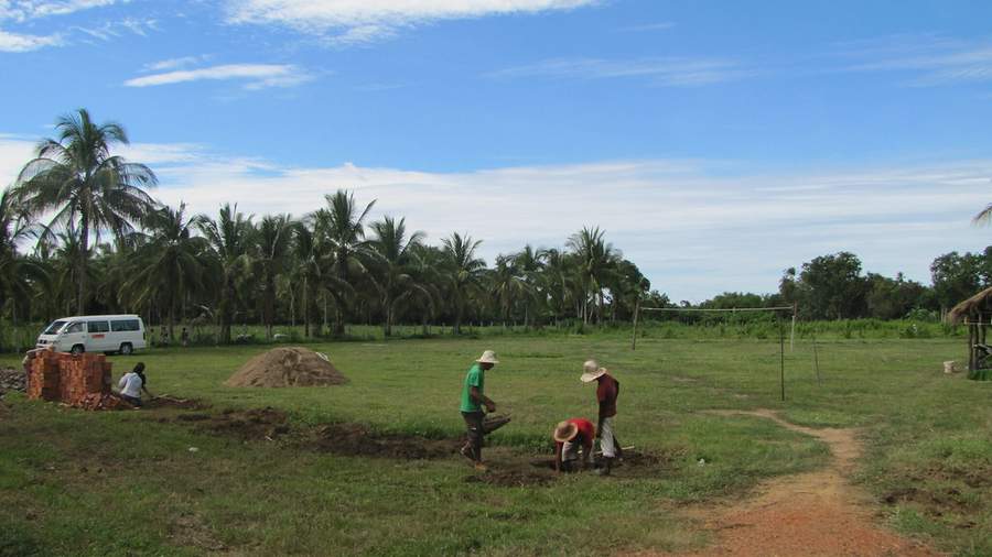 Workers digging in grassy field with bricks and white van