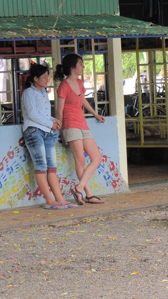Two women leaning against colorful painted wall at building
