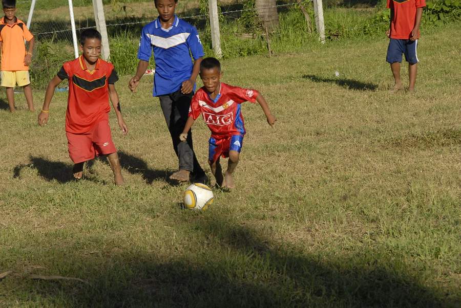 Children playing soccer on grass field