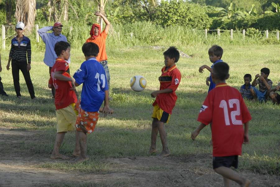 Children playing soccer on grass field in village