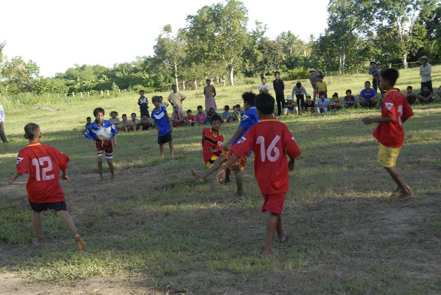 Children playing soccer with spectators on grass field