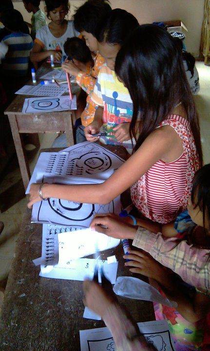 Children coloring pictures at classroom desk