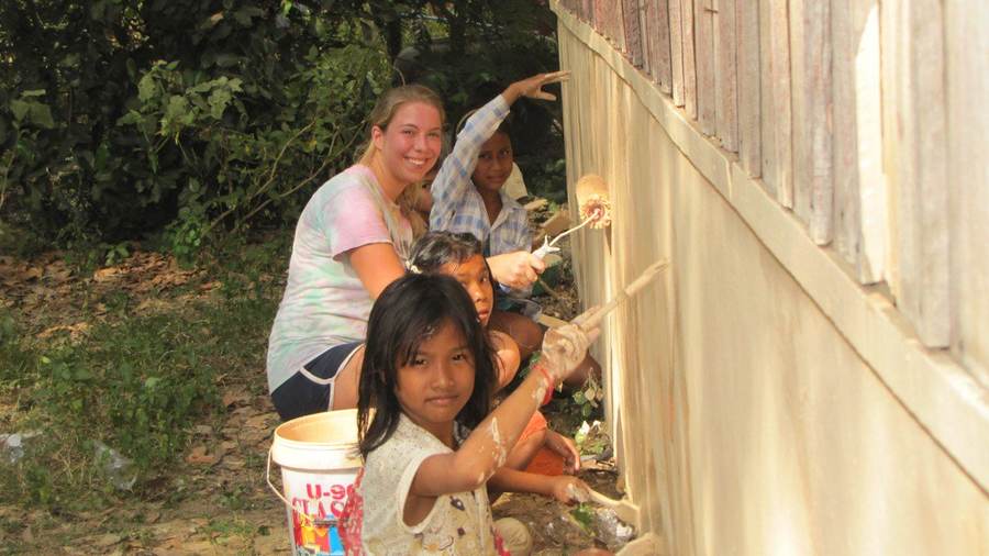 Woman and children painting building wall together