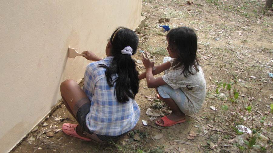Two girls painting building wall together