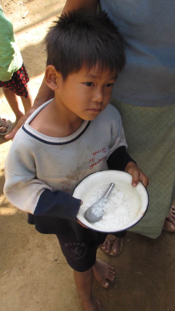 Young boy holding bowl of rice with spoon